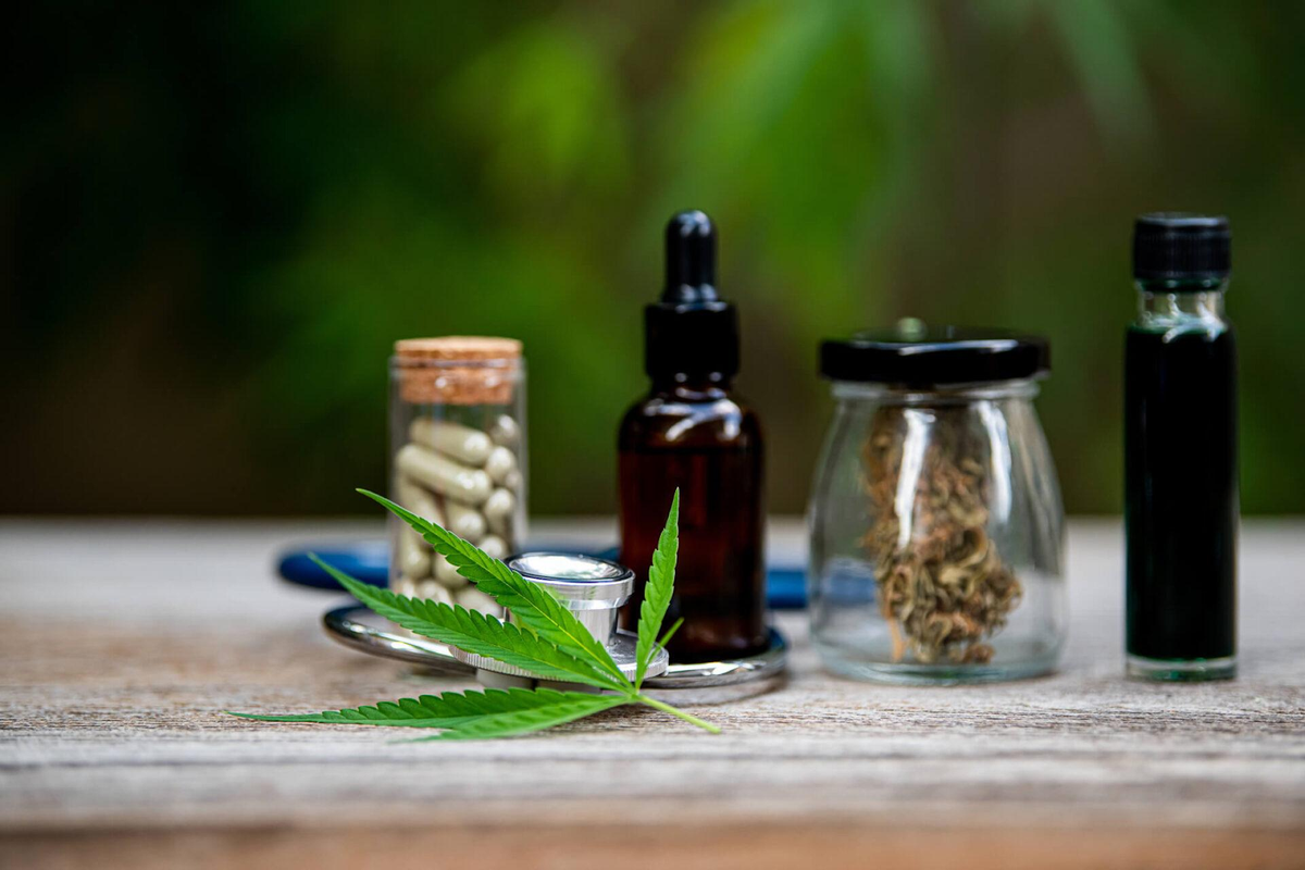 Cannabisblad met diverse gebruiksmethoden, waaronder olietincturen, gedroogde bloemen, capsules en vape-cartridges