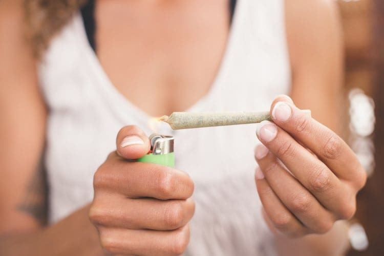 Persoon met een brandende joint en een groene aansteker in een lifestylescène