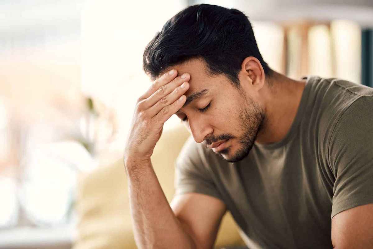 Man die zijn voorhoofd vasthoudt in een rustige binnenomgeving, ter illustratie van verlichting van stress en angst