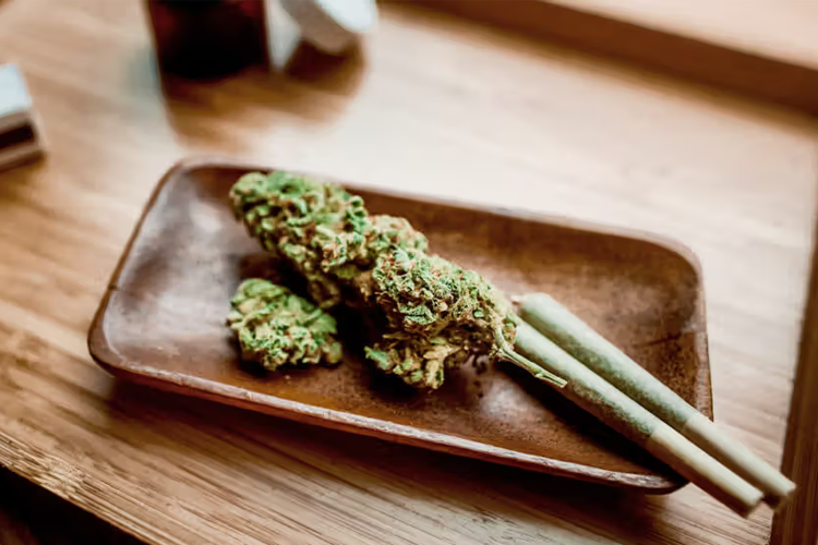 Cannabisbloemen en voorgerolde joints op een houten serveerplank